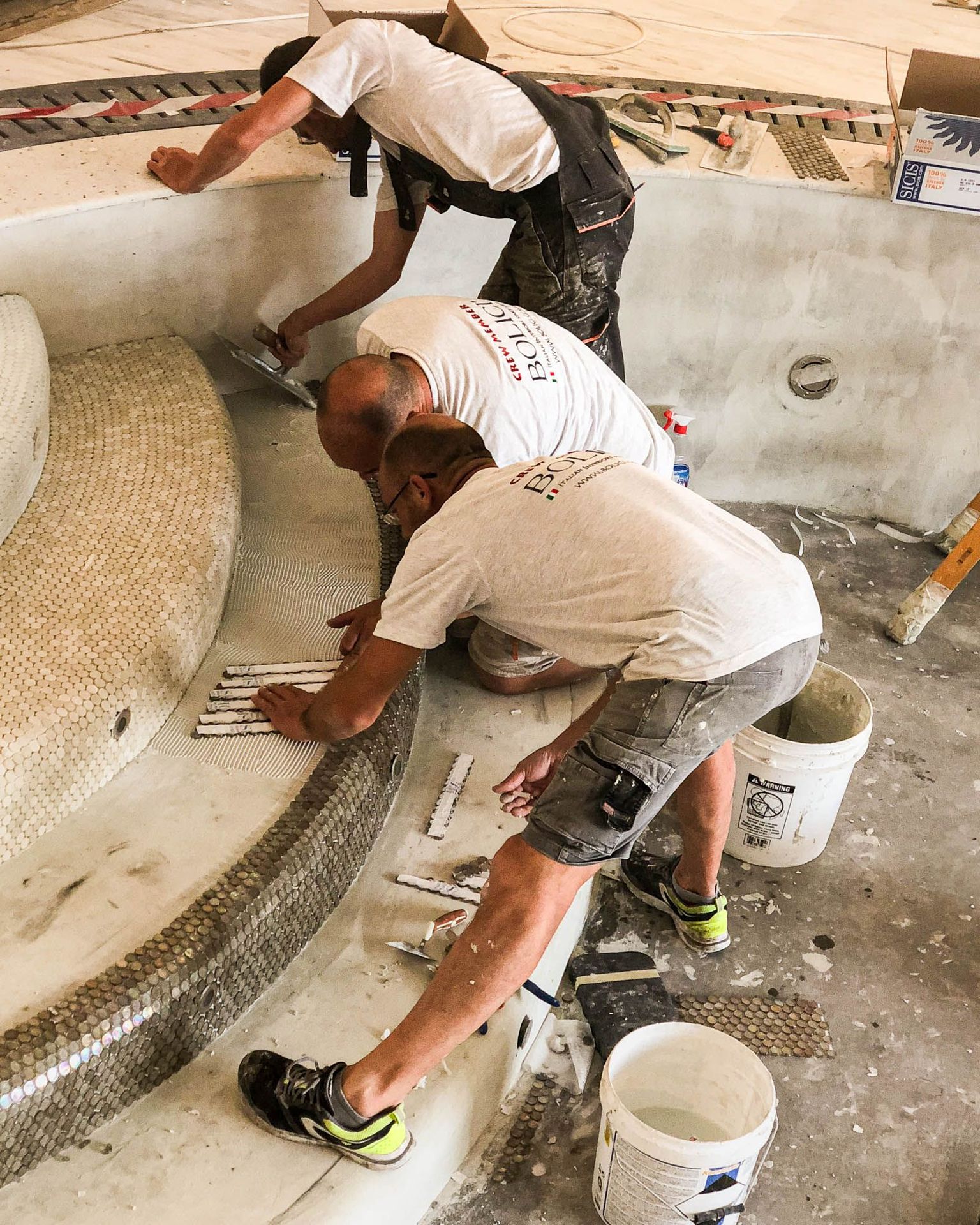 craftsmen installing mosaic finish on curved spa steps with care and precision